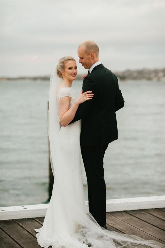 KWH real bride Gemma holds onto her new hubby. She wears her Jemma gown, a fit and flare high neck wedding dress.