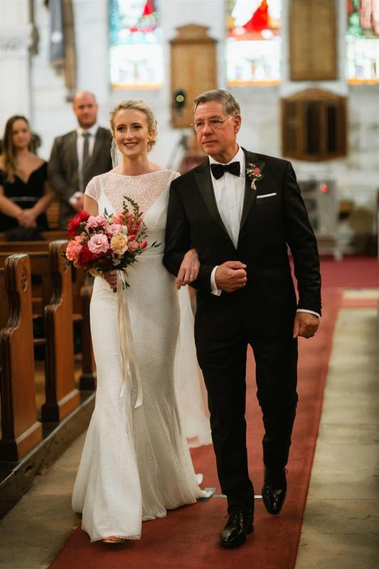 KWH real bride Gemma walks down the aisle with her dad at her church wedding. She wear the Jemma gown, a fit and flare lace wedding dress with open back.