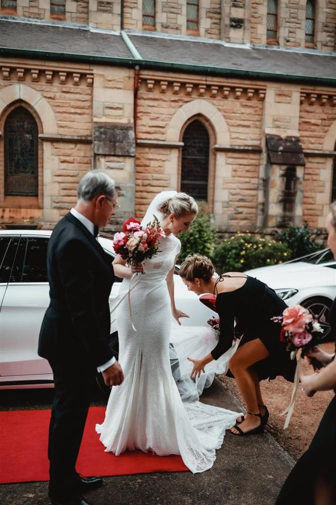 KWH real bride Gemma steps out of the limo with her dad onto the red carpet. She wears the ivory Jemma gown, a modern lace cap sleeve wedding dress.