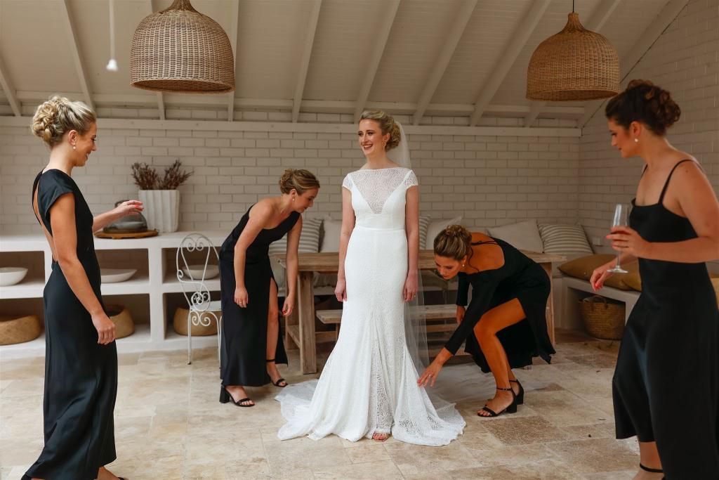 KWH real bride Gemma getting ready with her bridesmaids. She puts on her Jemma gown, a cap sleeve high neck lace wedding dress.