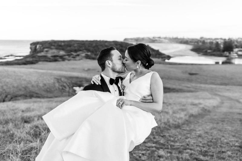 B&W image of KWH real bride Rebecca and Matthew kissing. She wears the Leonie Melanie gown, a modern a-line princess wedding dress.