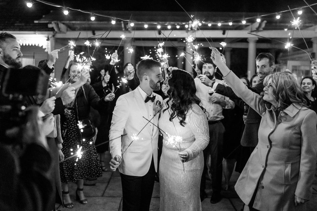 B&W image of KWH real bride Katherine and Conor leave their wedding through a sparkler send off. She wears the glamorous Margareta gown, a long sleeve beaded wedding dress