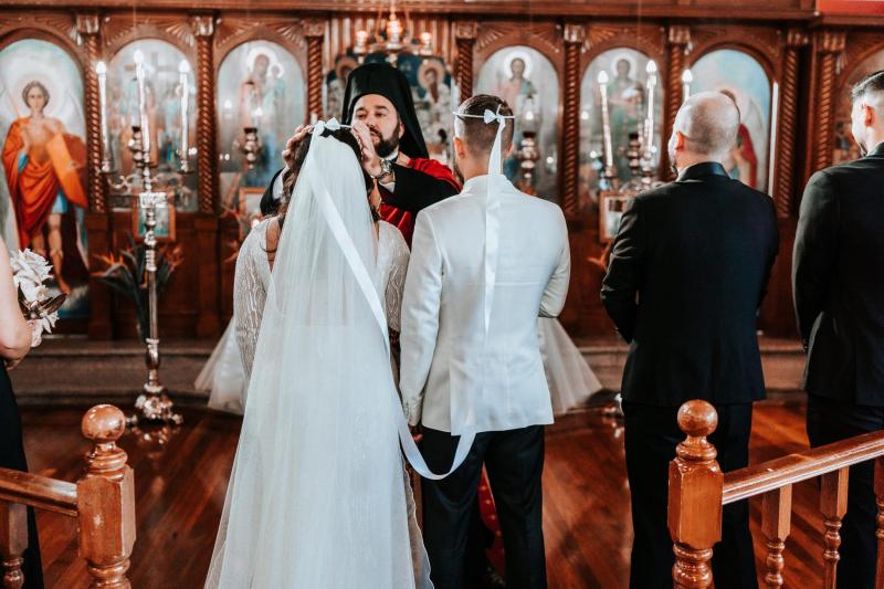 KWH real bride Katherine walks up the church stairs with Conor. She wears the gorgeous Margareta gown, a backless long sleeve beaded wedding dress.