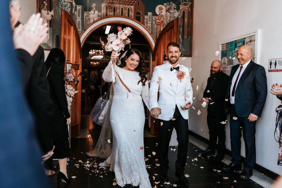 KWH real bride Katherine walking out of the church with Conor as she wears her stunning Margareta gown, a long sleeve beaded wedding dress