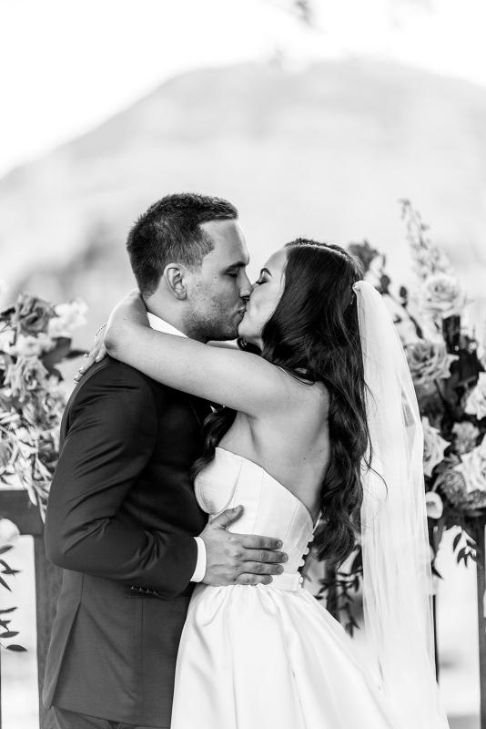 B&W image of KWH real bride Hannah and Reece kissing at the alter. She wears the Blake Camille gown, a modern strapless aline wedding dress.