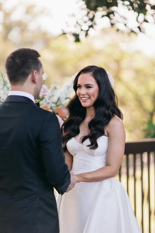 KWH real bride Hannah looks into Reece's eyes at their vows. She wears the stunning Blake Camille gown, a modern strapless aline wedding dress.