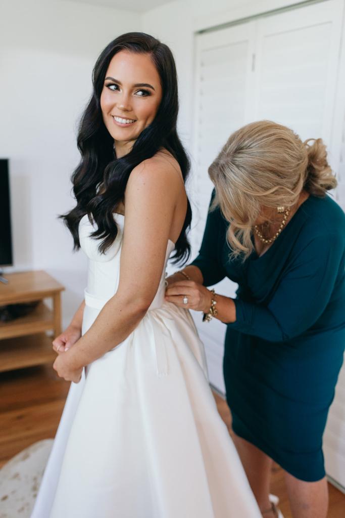 KWH real bride Hannah has her mom do the buttons on her Blake Camille gown, a modern strapless aline wedding dress.