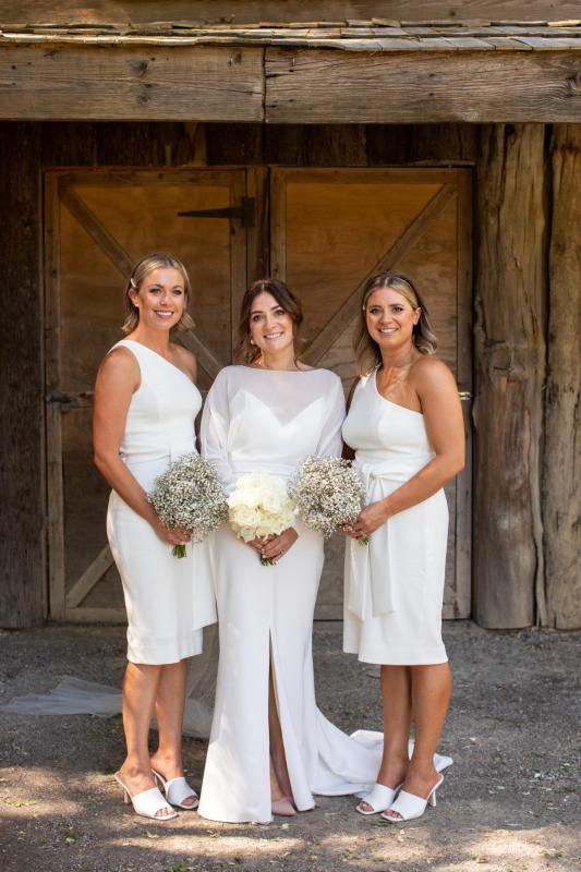 KWH real bride Erin stands with her bridesmaids. She wears the modern Brie gown, simple wedding dress with high neck and long sleeves.
