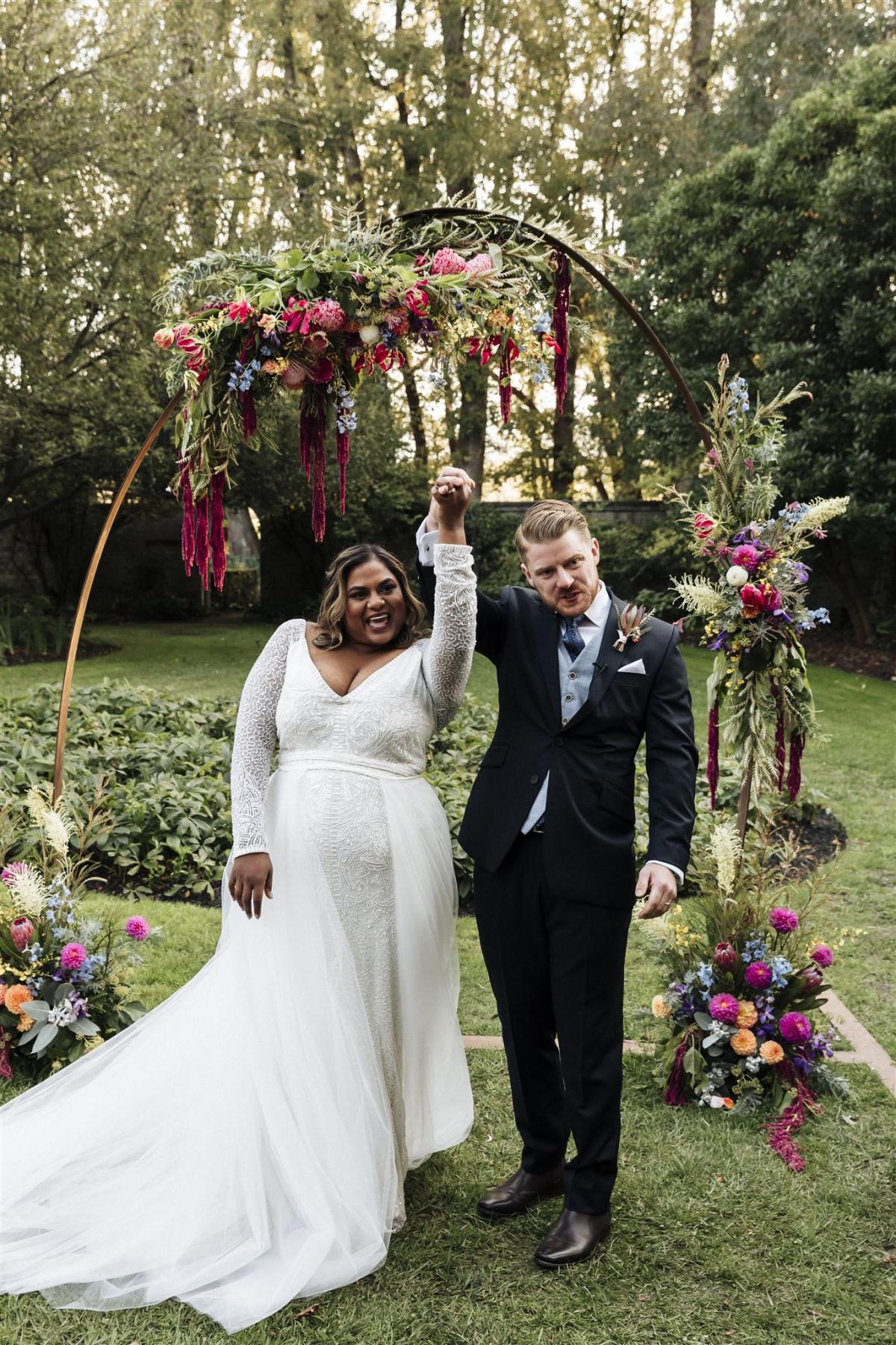 KWH real bride Nalini and Michael walking down the aisle as she wears the Celine gown with Alice train, a v-neck beaded wedding dress.
