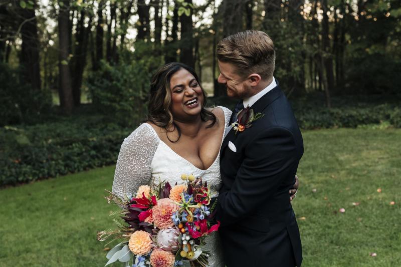 KWH real bride Nalini and Michael laugh with each other. She wears the Celine gown, v-neck fit and flare beaded wedding dress.