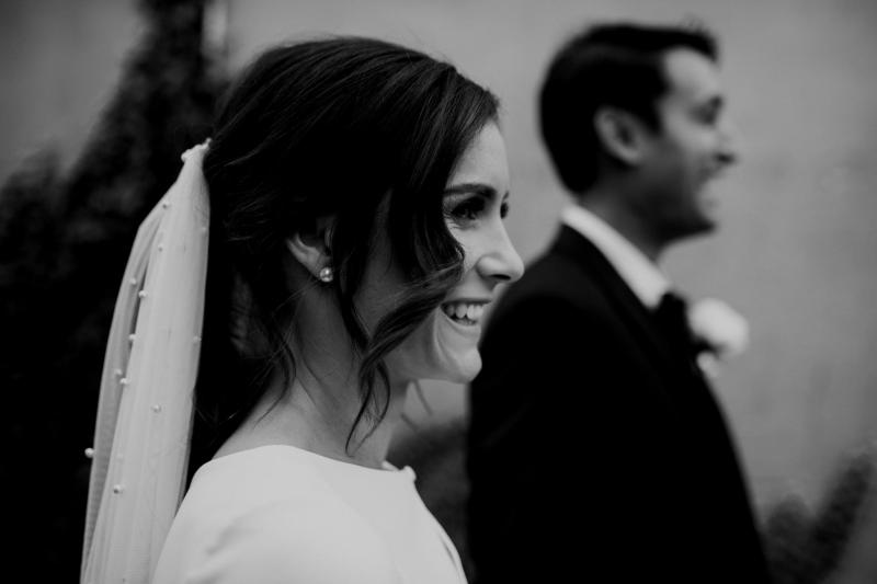 B&W image of KWH real bride Jacqui smiles as she wears her Clarrisa gown with her Pearl veil; a ivory fit and flare wedding dress.