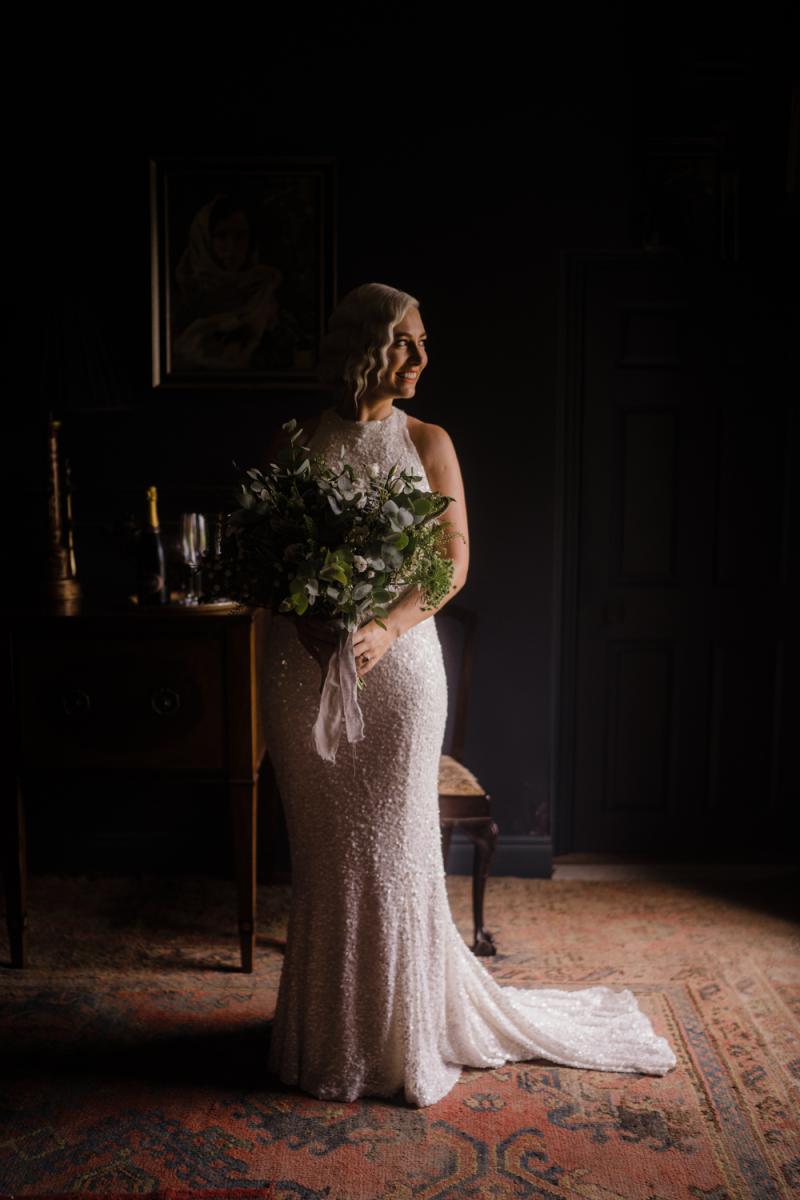 KWH real bride Laura stands for her bridal portrait. She wears the Cindy gown, a halter neck sequin wedding dress.
