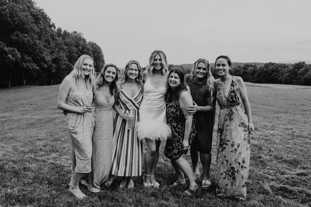 B&W image of KWH real bride Kasey with her friends as she wears her Sherry mini gown, a simple short wedding dress with open back and feather detail.