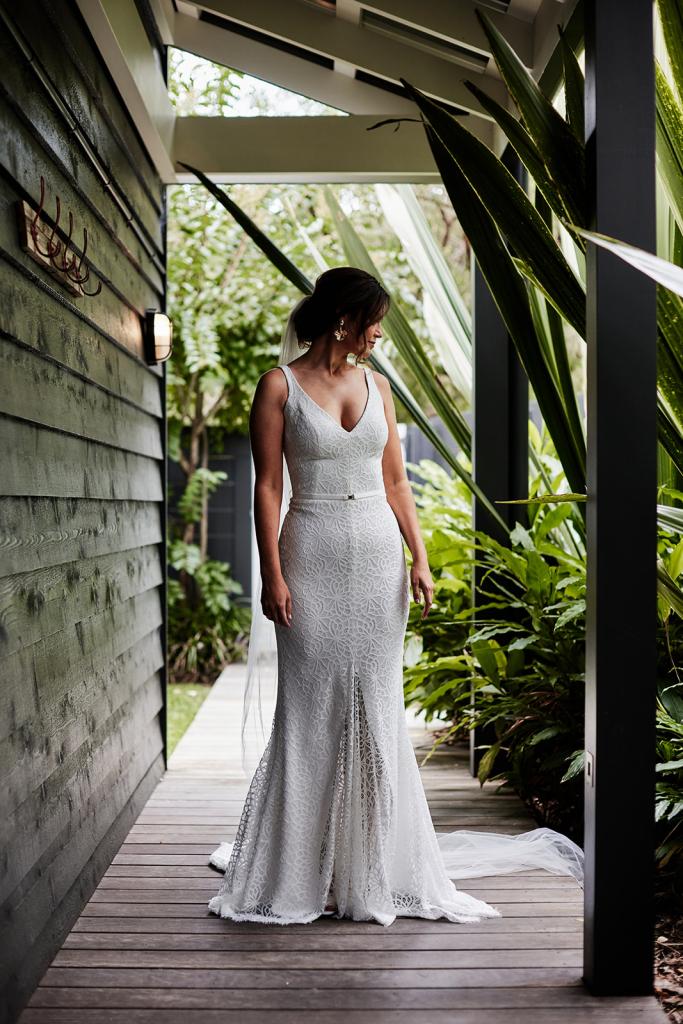 KWH Real bride Emma standiing on a porch in her effortless Rylie gown, a modern lace fit and flare wedding dress.