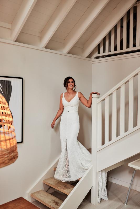 KWH real bride Emma walks down the stairs in her Rylie gown, a lace fit and flare wedding dress with v neckline.