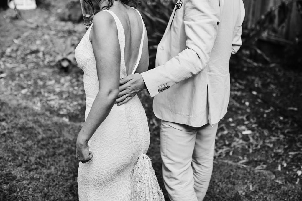 B&W image of KWH real bride Emma and will walking. She wears the low back Rylie gown, a modern lace fit and flare wedding dress.