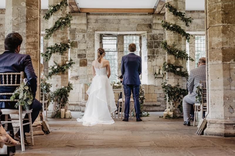 KWH real bride Monica and James stand at their castle ceremony. She wears the Anya gown, a modern fit and flare beaded wedding dress with detachable Diamond trains.