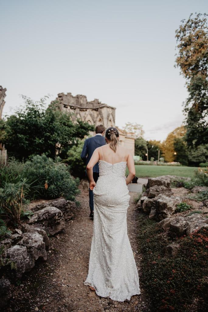 KWH real bride Monica is led off my her new husband James into a gardne. She wears the Anya gown, a elegant fit and flare beaded wedding dress.