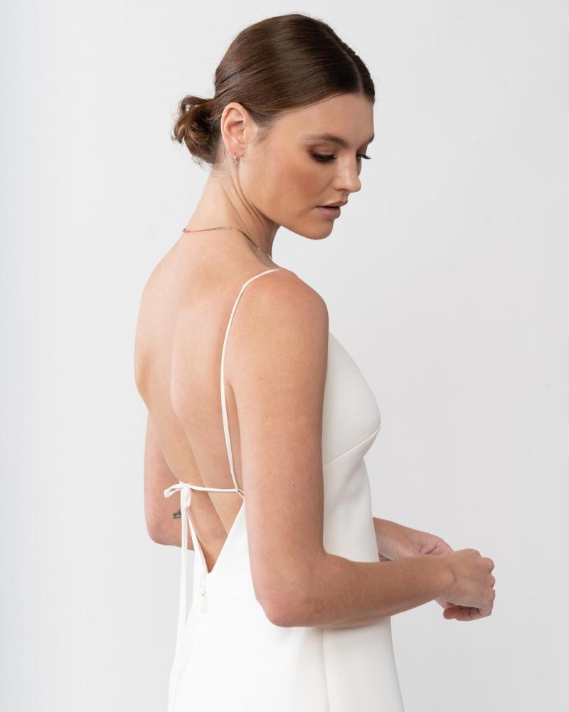 Upclose studio shot of the Isadora gown by Karen Willis Holmes , a minimalist crepe wedding dress with shoe string straps and V-neckline.