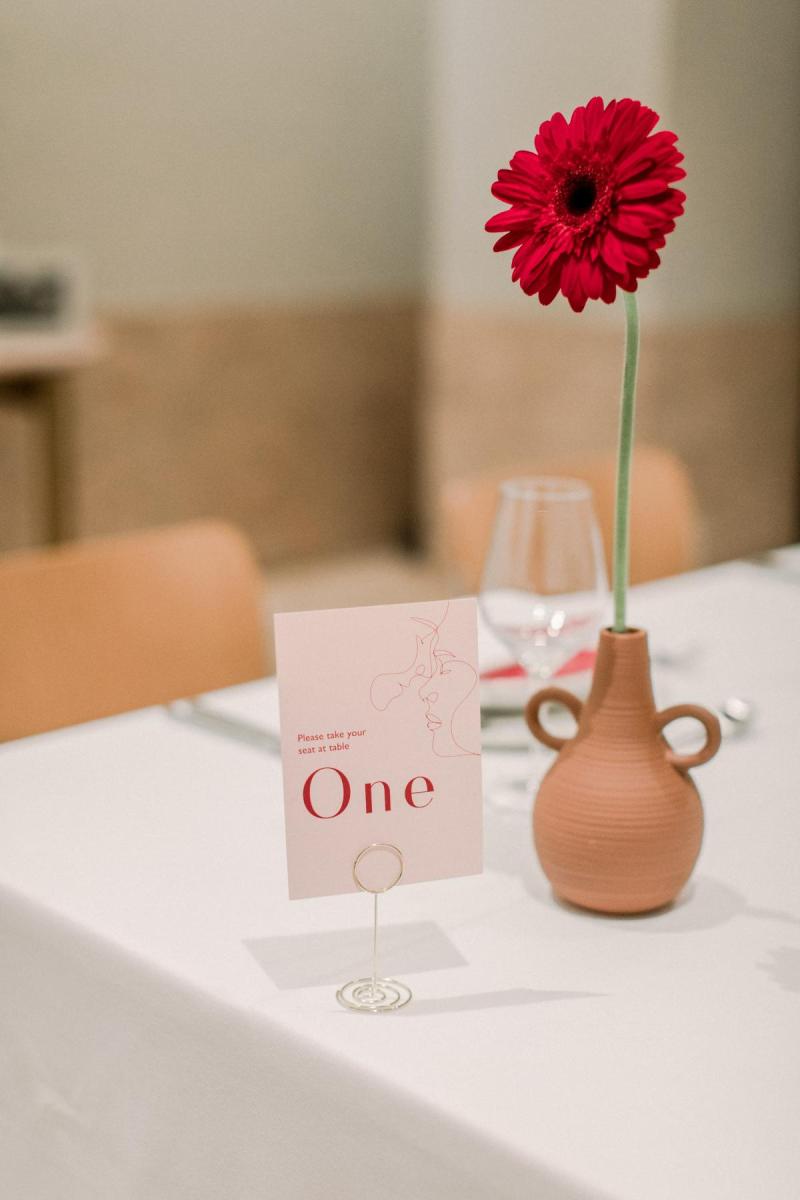 KWH real bride Josey's minimalist reception decor with terrocata bud vases and pops of bright red flowers.