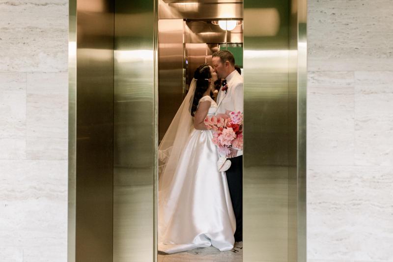 KWH real bride Josey and Brad walk across the street as she wears her flowy Taryn Camille gown, a modern aline wedding dress with U-shaped neckline.