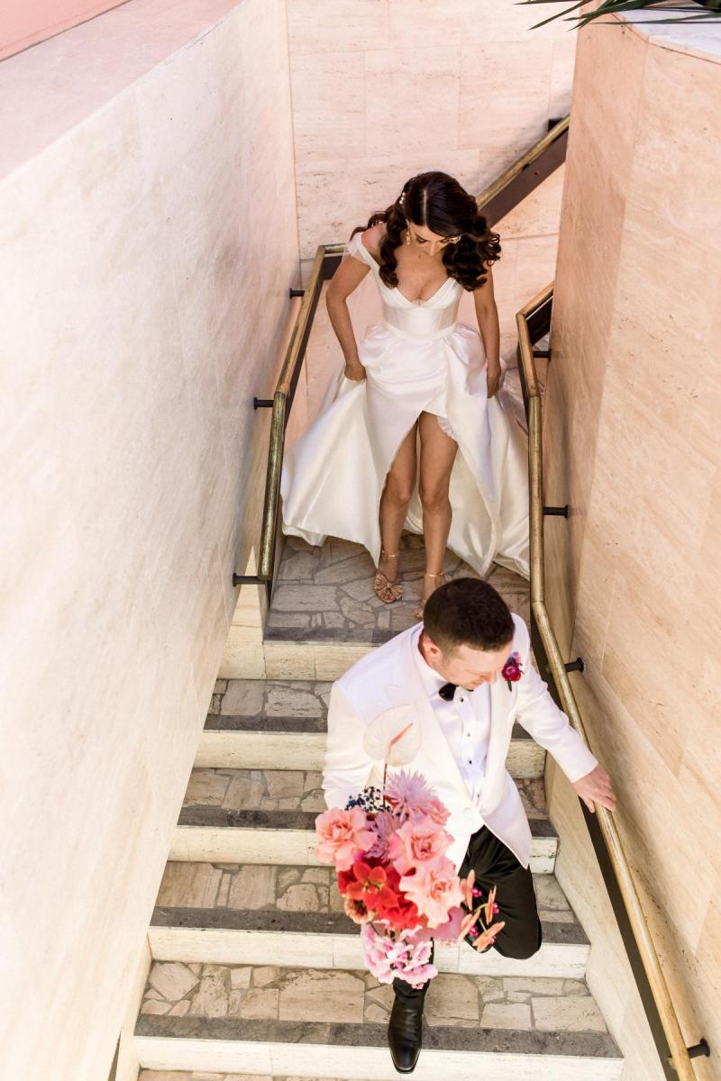 KWH real bride Josey and Brad walk down the stairs in her Taryn Camille gown , a modern aline wedding dres with high leg split.