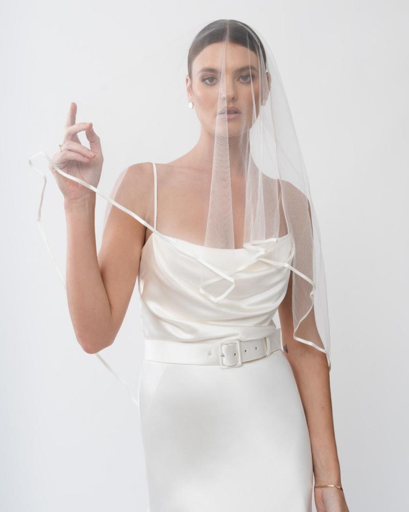The Tiffany gown and Florence wedding veil by Karen Willis Holmes, a straight neckline, simple satin wedding dress with spaghetti straps.
