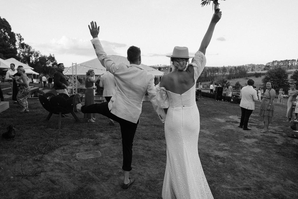 Vivienne-by Karen Willis Holmes, Vivienne finishes in a soft V at the back shown by bride will she holds her bouquet of flowers in the air