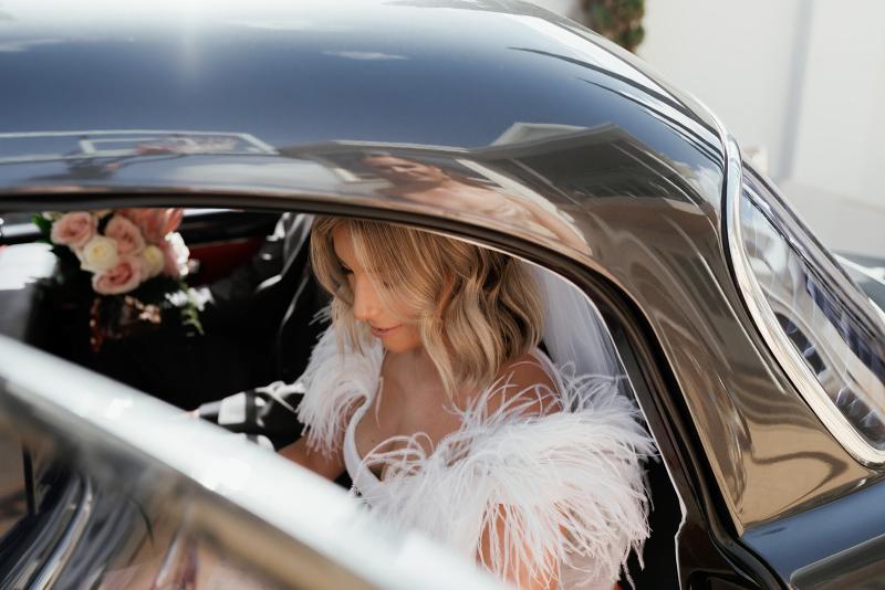 Annabelle by Karen Willis Holmes, Annabelle showcases her ostrich feather detailing at the shoulder as seen on our bride while to steps out of the car