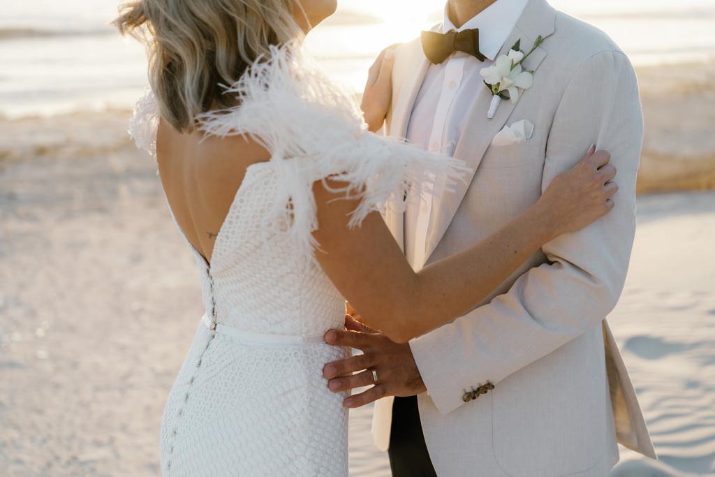 Annabelle Gown by Karen Willis Holmes, with an open back while holding husband on a romantic beach during sunset