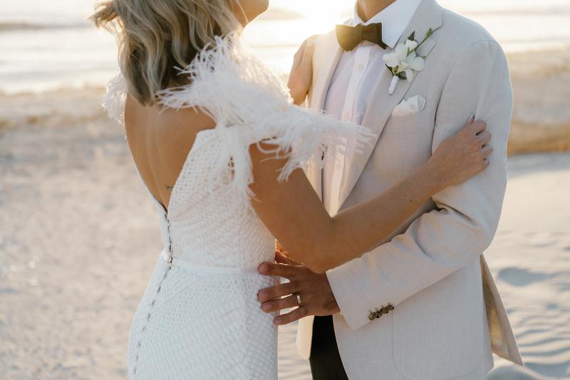 Annabelle Gown by Karen Willis Holmes, with an open back while holding husband on a romantic beach during sunset