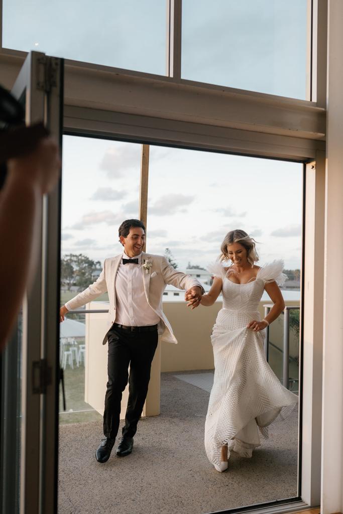 Annabelle by Karen Willis Holmes, bride and groom running into their reception, while bride holds on to her beautfiul long train