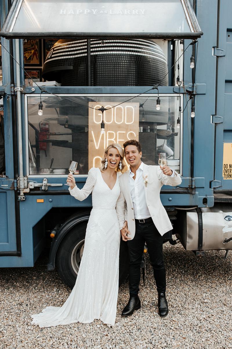Perry Gown-Karen Willis Holmes, The bride and Groom celebrating in front of happy as Larry Pizza Truck in her beautfiul Perry Gown