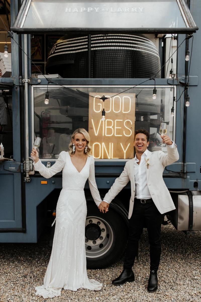 Perry Gown-Karen Willis Holmes, The bride and groom cheering with champagne while she looks gorgeous in our Perry Gown