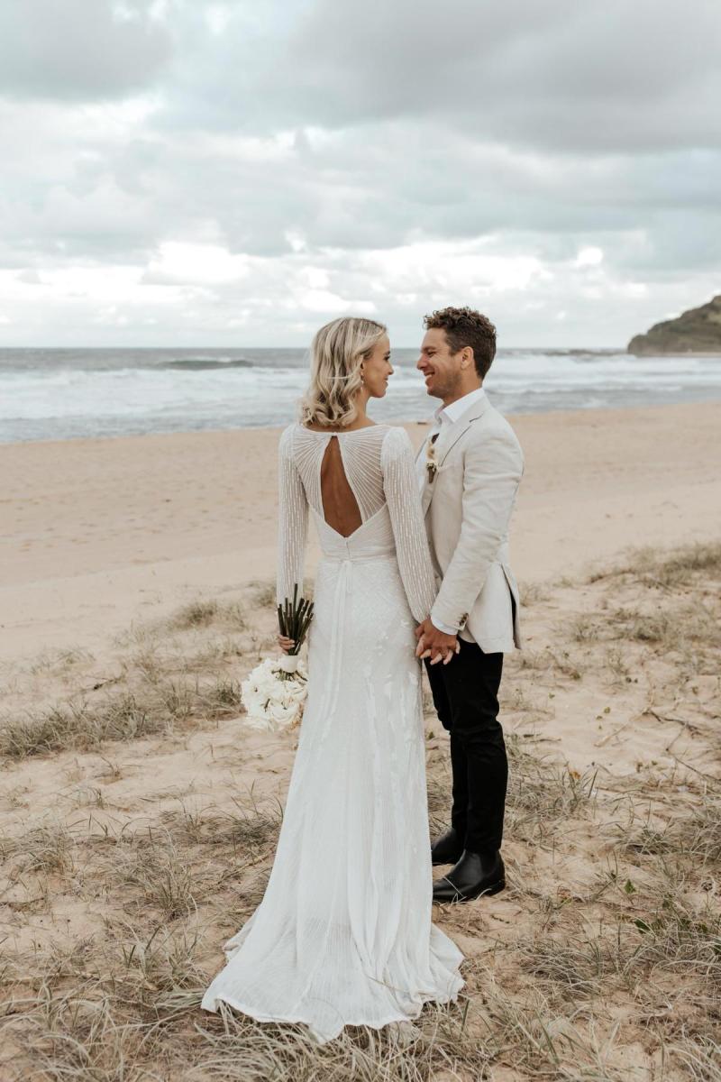 Perry Gown-Karen Willis Holmes, Bride and groom at isolated beach for wedding photos while holding hands