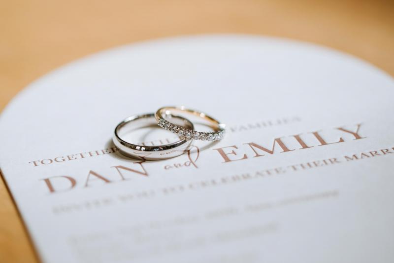 Real bride Emily and Dan's marital rings on top of their wedding invite.