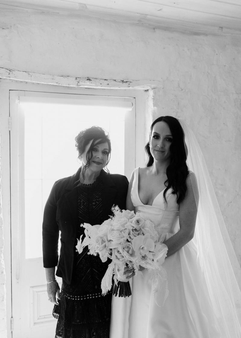 KWH real bride stands with her mom pre-ceremony for a black and white portrait. She wears the timeless Taryn Camille gown from KWH.