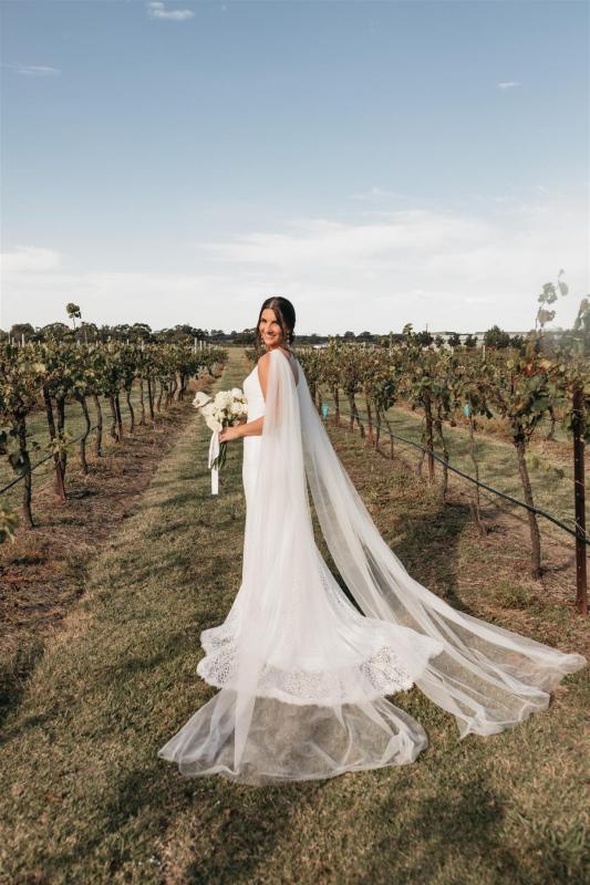 Lorissa & Recce-Rylie-WILD HEARTS collection - Bride Lorissa seen in vineyard, holding flower bouquet, while wearing our effortless Rylie Gown