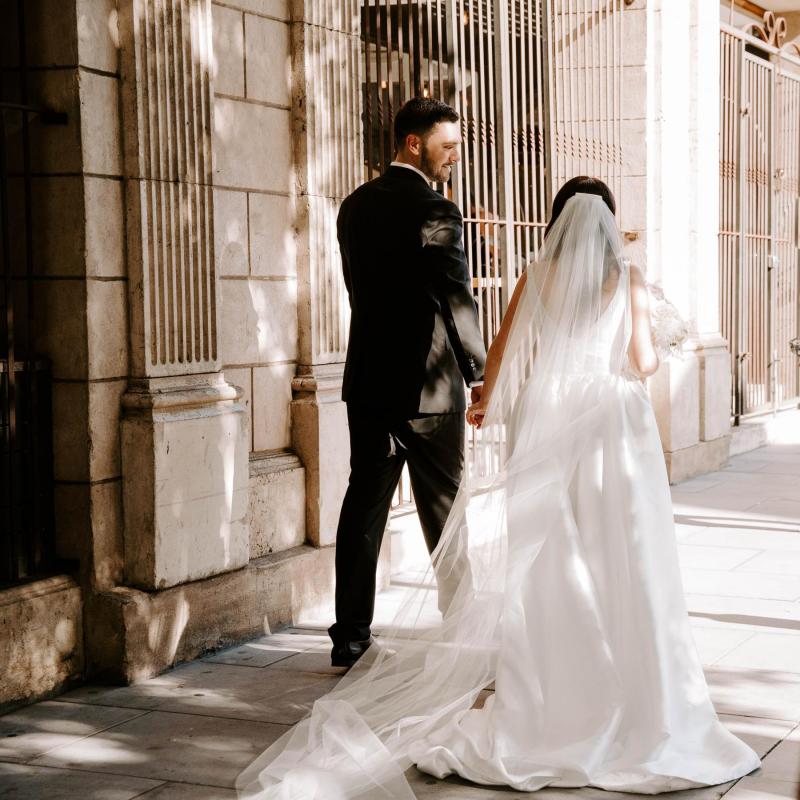 Real bride Shenea and new husband Lain walk down the street holding hands. She wears the effortless Taryn Camille gown by KWH.