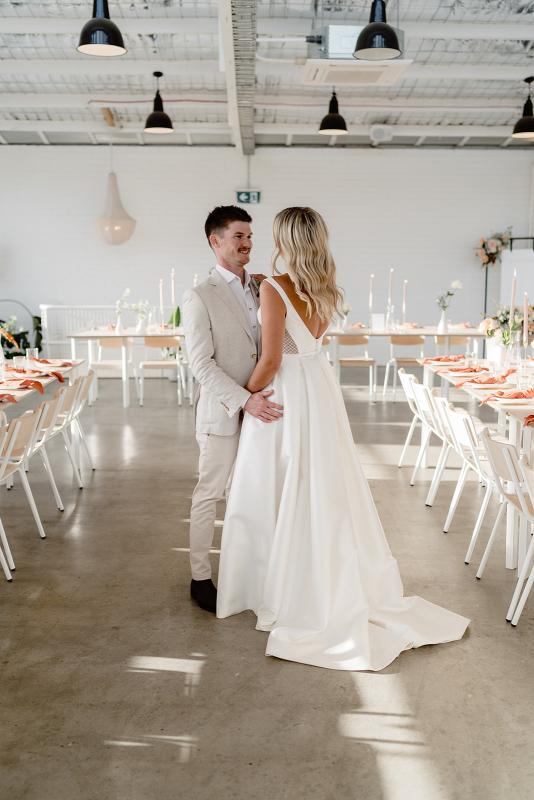 Shelly Elizabeth-Karen Willis Holmes- Jade & Matt - Bride and groom seen holding hands in their modern venue, while bride wears the beautiful Shelly bodice and the Elizabeth skirt which is perfect for our brides wanting a modern grandeur ball gown on your wedding day.