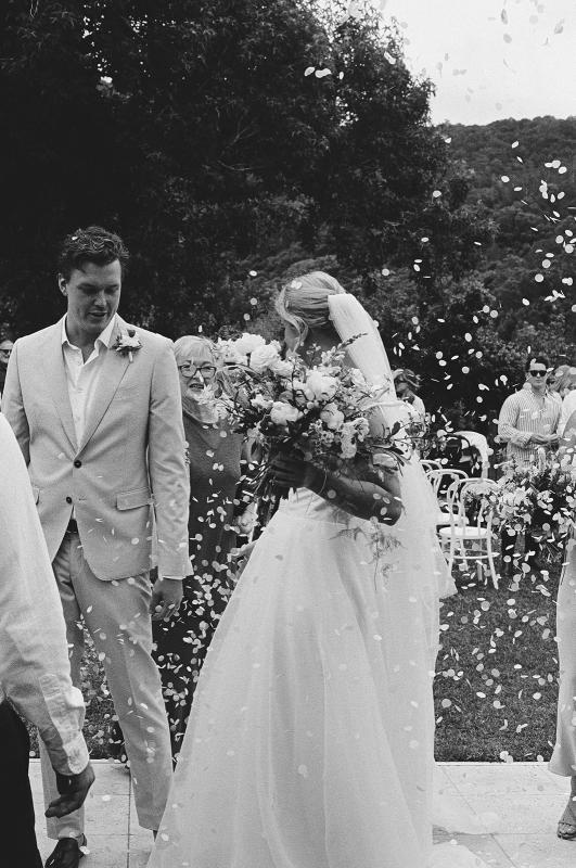 Taryn & Joni - Karen Willis Holmes - BESPOKE - Madeline & Joe - bride and groom seen holding hands and celebrating their marriage