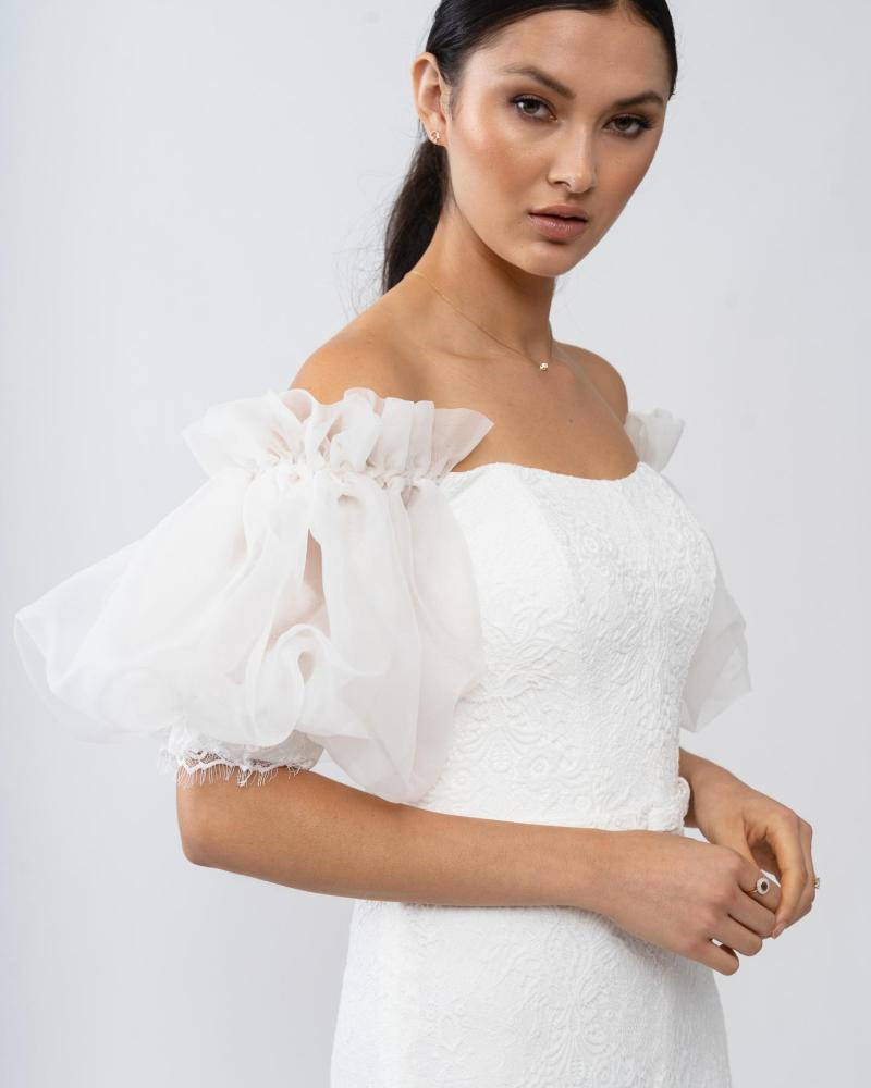 The Wynter gown by Karen Willis Holmes, a strapless neckline, puff sleeve lace wedding dress with a fit and flare shape and a split skirt.
