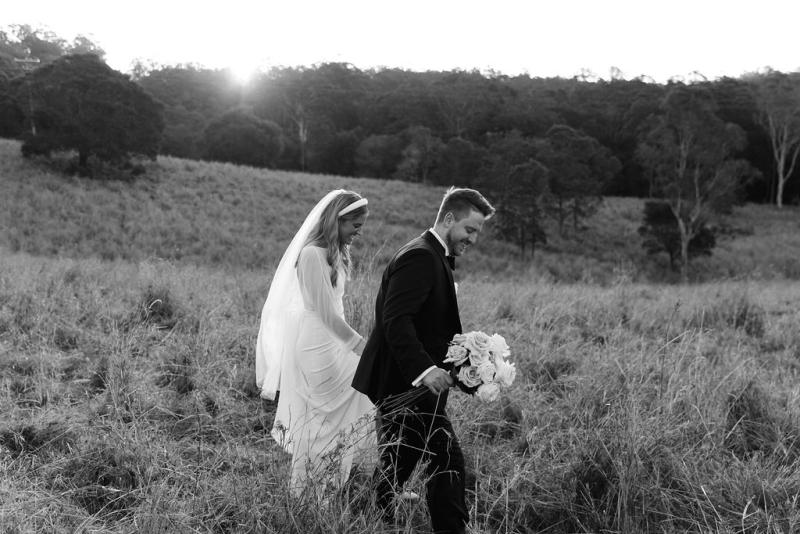 Brie-Karen Willis Holmes - Taylor & Angus - Bride and groom exploring their country side wedding venue, while holding hands and Floral bouquet