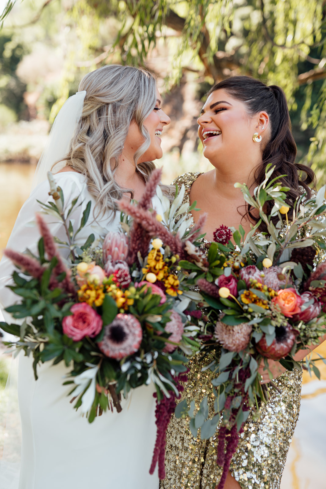 Nikki - Karen Willis Holmes - Sarah & Gabriella- Lgbt wedding, full of bold and unique elements. Same sex couple seen holding each other for their couple portraits, with their colorful and Australian natives floral arrangements. Brides are wearing a classic, long sleeve wedding dress.