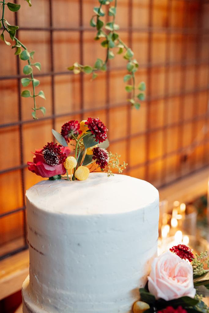 Nikki - Karen Willis Holmes - Sarah & Gabriella- Same sex couple get married at a unique wedding venue, full of bold, earthy and rustic elements. Bride and bride has chosen a classic wedding cake with fresh florals designed on it.