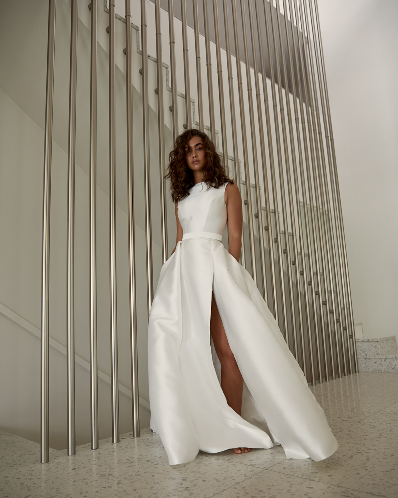 The Harper Kirsten is a classic wedding dress with a modern edge, featuring a boat neckline and open back, Aline skirt with thigh high split by Karen Willis Holmes 2023 Bridal Campaign