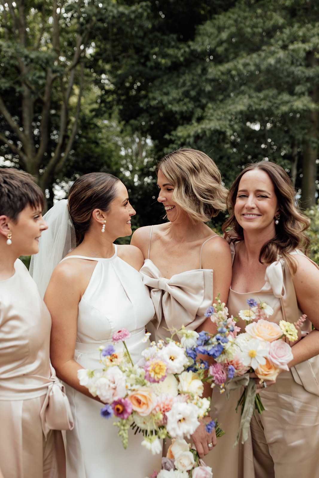 Layne by Karen Willis Holmes-halter neckline wedding dress-Jessica & Tim- Bride is seen taking wedding photos with her beautiful bridesmaids, wearing soft champagne and pink toned dresses. Bride has chosen the classic Layne gown from the BESPOKE collection, featuring a sophisticated high neck line.