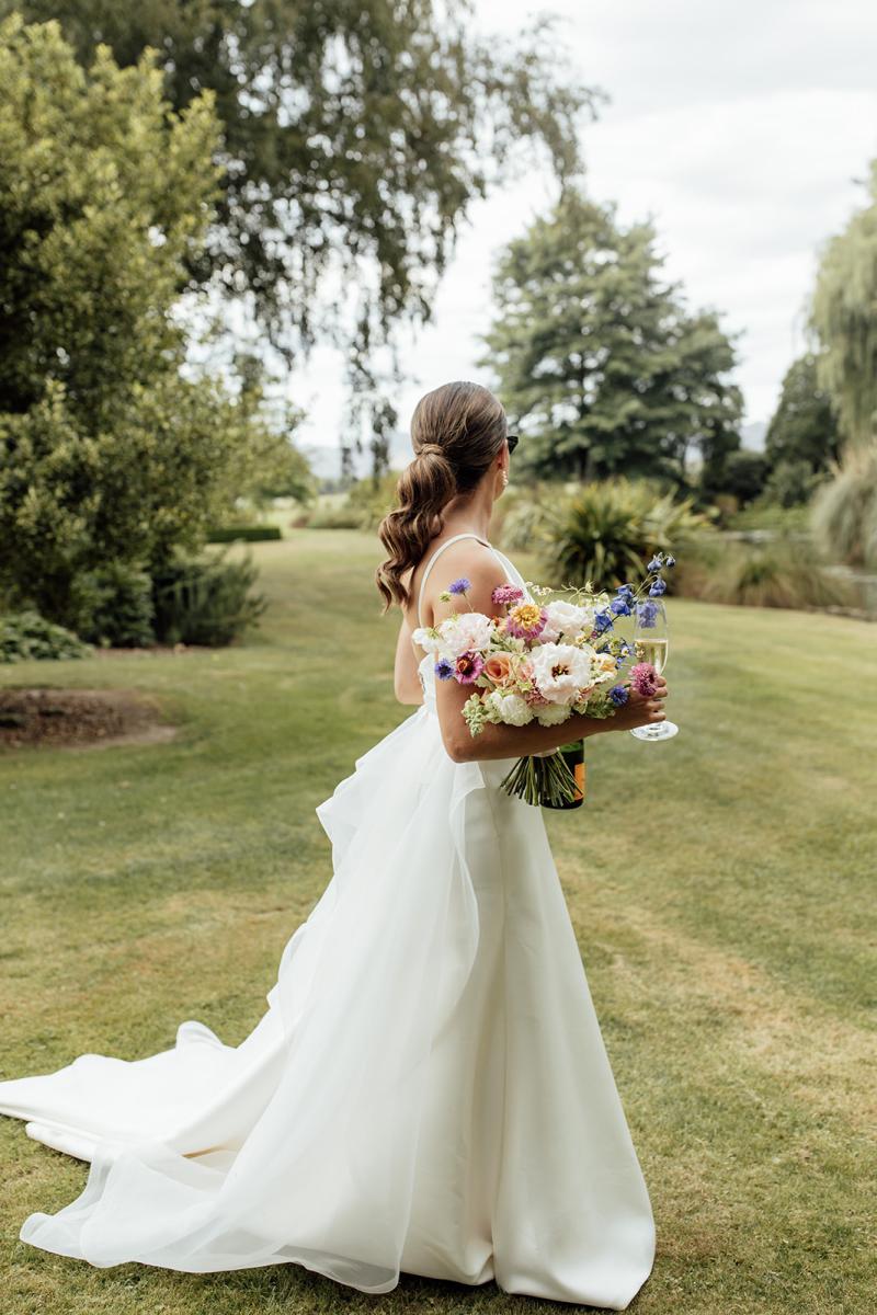 Layne by Karen Willis Holmes-halter neckline wedding dress-Jessica & Tim- Bride is seen dancing in the gardens of her venue in new Zealand, holding soft pastel coloured florals.
