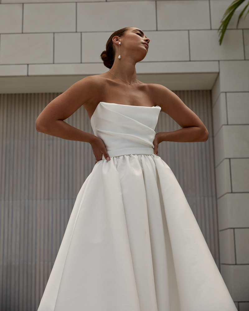 Lou Lou Sabrina is a classic Wedding dress with a draped corset bodice featuring a full, pleated skirt, modern side split and pockets by Karen Willis Holmes 2023 Bridal Campaign.