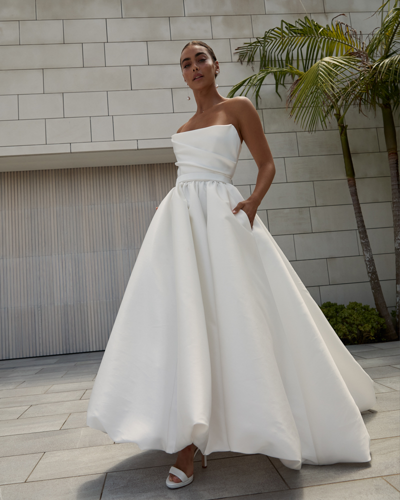 Lou Lou Sabrina is a classic Wedding dress with a draped corset bodice featuring a full, pleated skirt, modern side split and pockets by Karen Willis Holmes 2023 Bridal Campaign.